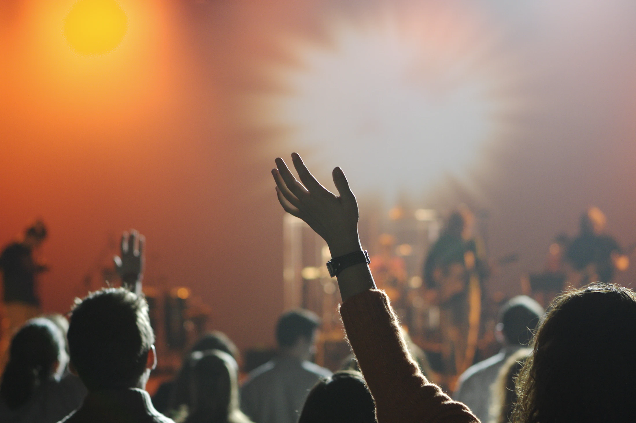 Igreja em adoração, com uma mão levantada contra a luz